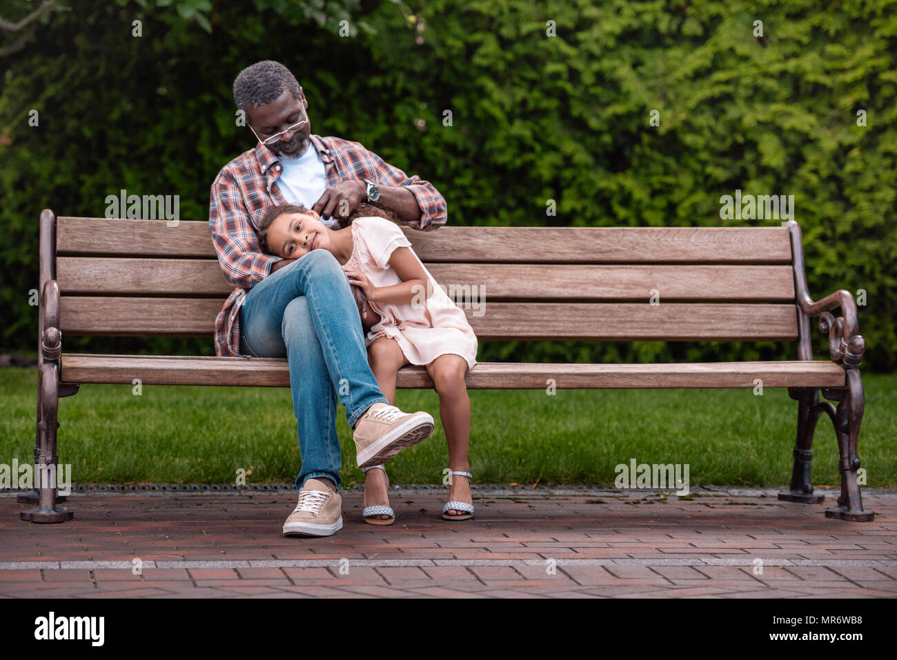 Adorable african american girl et son grand-père assis sur un banc dans le parc Banque D'Images