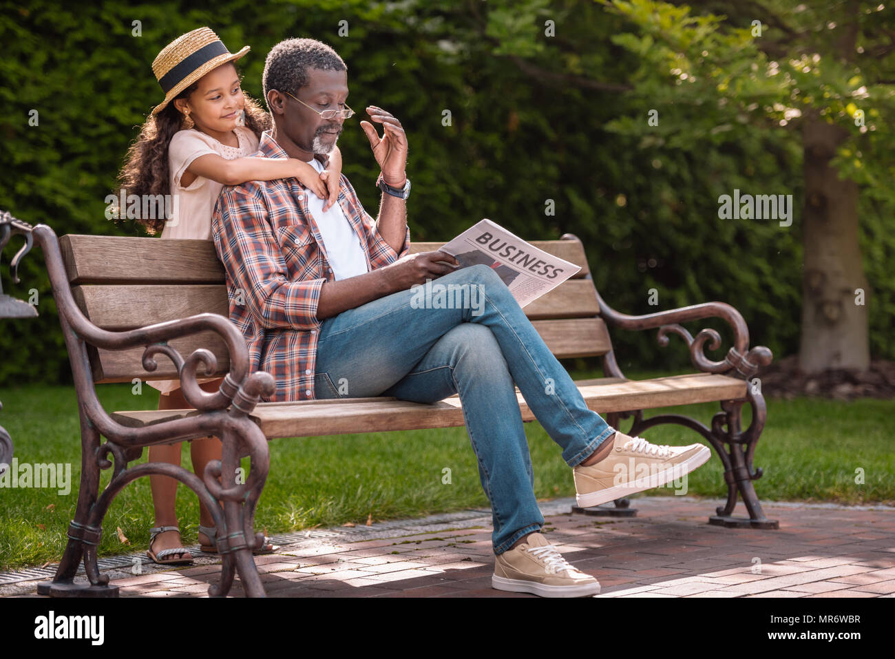 Adorable african american granddaughter hugging son grand-père assis sur un banc dans le parc Banque D'Images