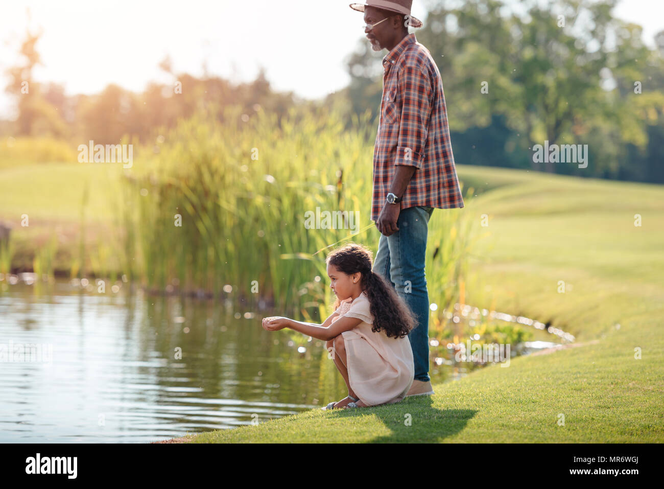 African American petite-fille et son grand-père se tenant ensemble près du lac dans le parc Banque D'Images