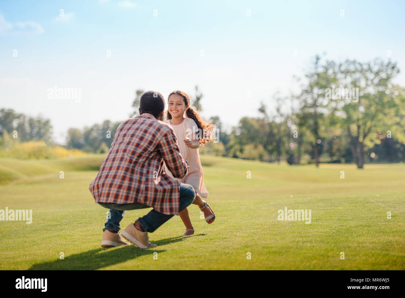 Smiling african american petite-fille courir à grand-père sur pelouse verte dans la région de park Banque D'Images