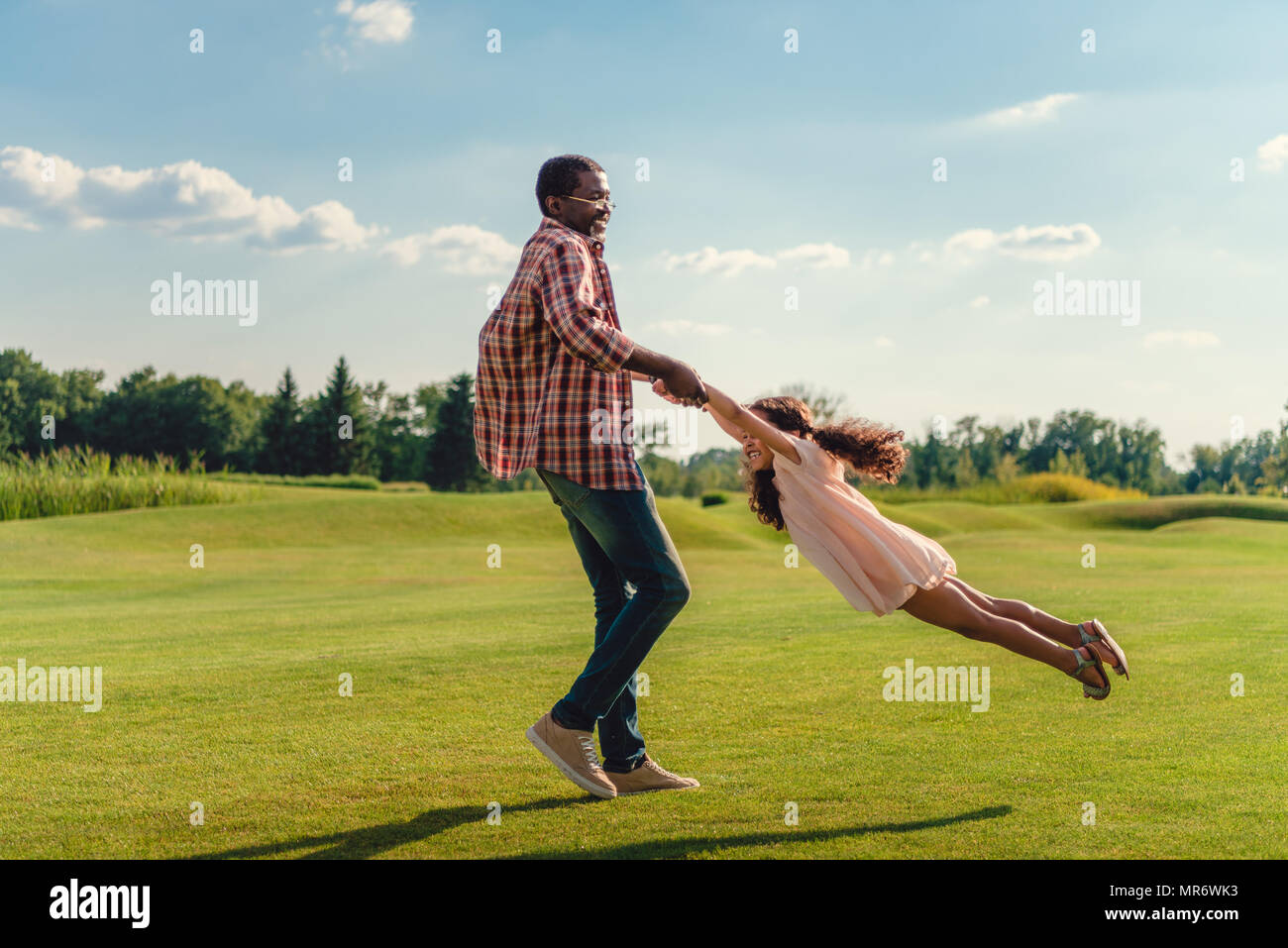 Happy african american grand-père jouant avec sa petite-fille sur pelouse verte Banque D'Images