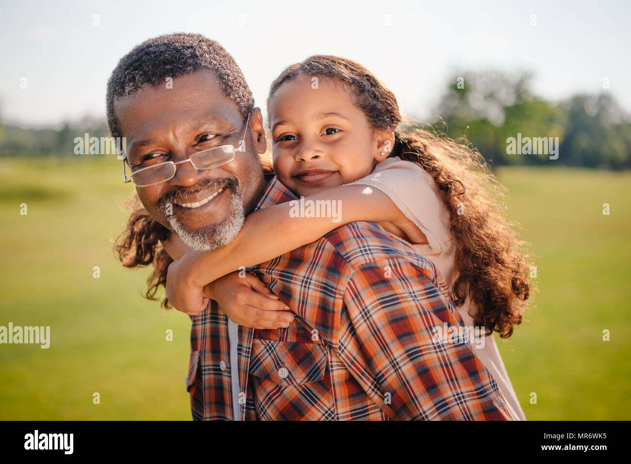 Happy african american granddaughter hugging her smiling grandfather sur pelouse verte Banque D'Images