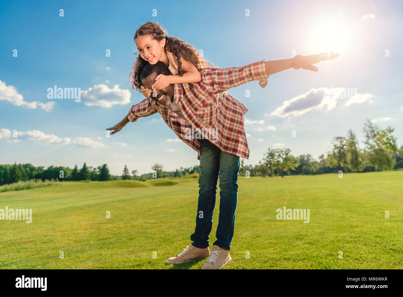 African American grand-père-fille donner piggyback ride sur pelouse verte avec l'afficheur Banque D'Images