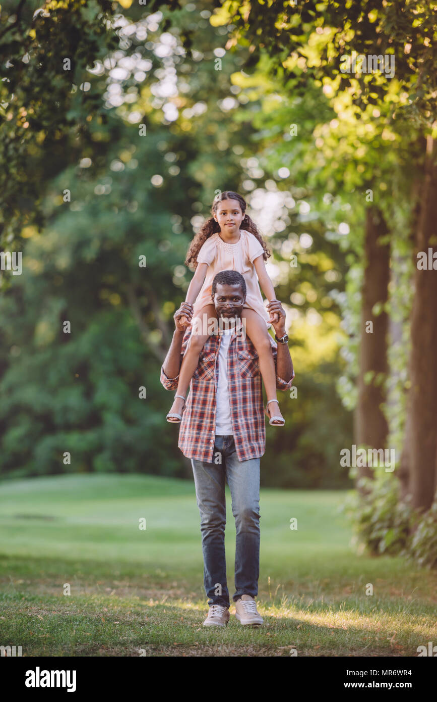 African American grand-père s'occuper sa petite fille sur les épaules en park Banque D'Images