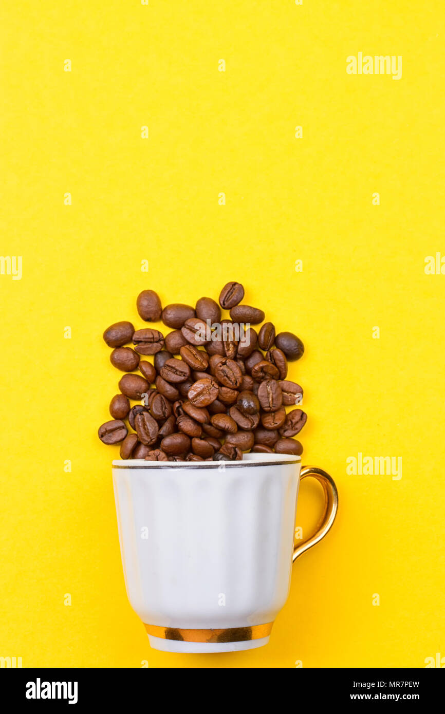 Les grains de café renversé sur une tasse sur le yellowbackground Banque D'Images