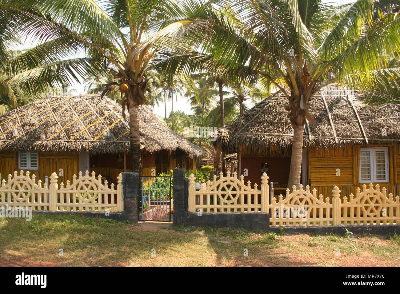 Les huttes au toit de chaume, les piquets de clôture et palmiers, Varkala, Inde Banque D'Images