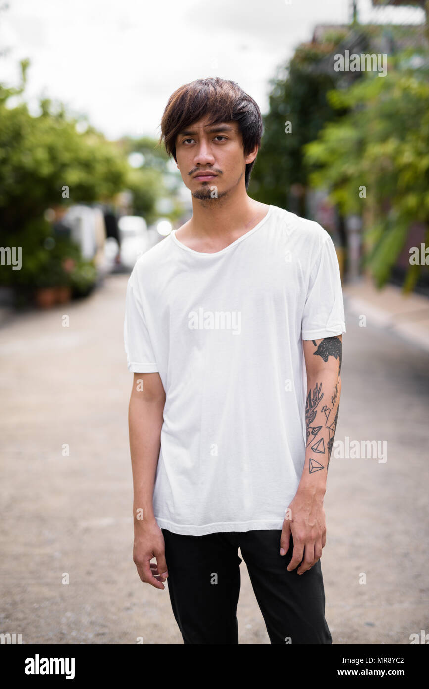 Jeune homme asiatique avec des tatouages à la main dans les rues à l'extérieur Banque D'Images