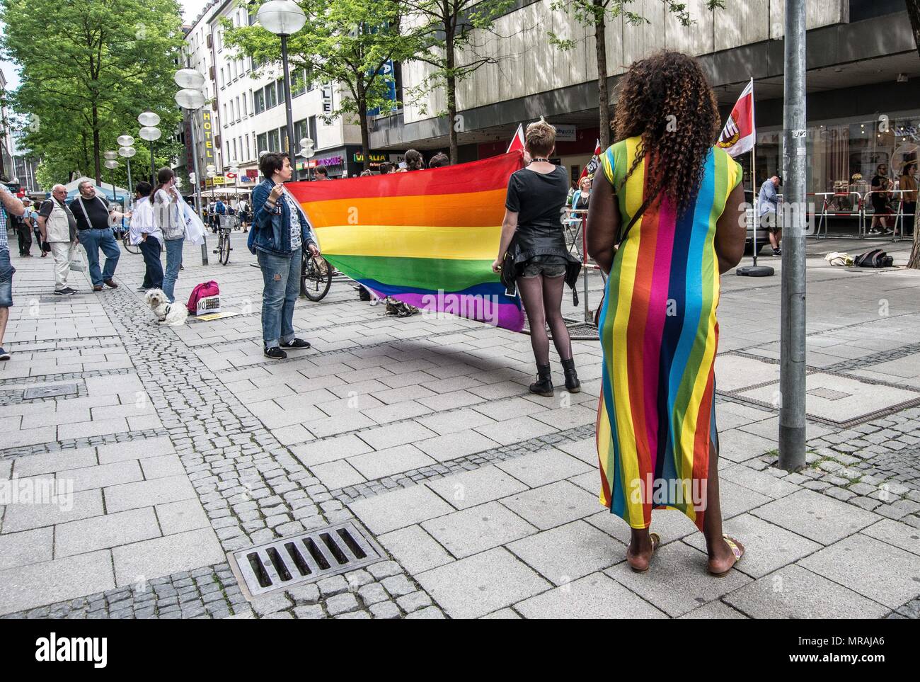 Munich, Bavière, Allemagne. 26 mai, 2018. Une femme dans une robe arc-en-ciel se tient devant un drapeau arc-en-ciel tenue par les manifestants contre le parti néo-nazi NPD à Munich. Détenus par les États parties, l'Werlberger Renate néo-nazi NPD (Parti National Demokratische Partei) a tenu un rassemblement dans le centre-ville de Munich afin de s'exposer à des milliers de passants et touristes. Frank Auterhoff a été invité à partir de Franken comme président. Un participant a des accusations criminelles déposées par la police pour avoir prétendument donnant un néo-nazi à trois doigts signe. Credit : Sachelle Babbar/ZUMA/Alamy Fil Live News Banque D'Images