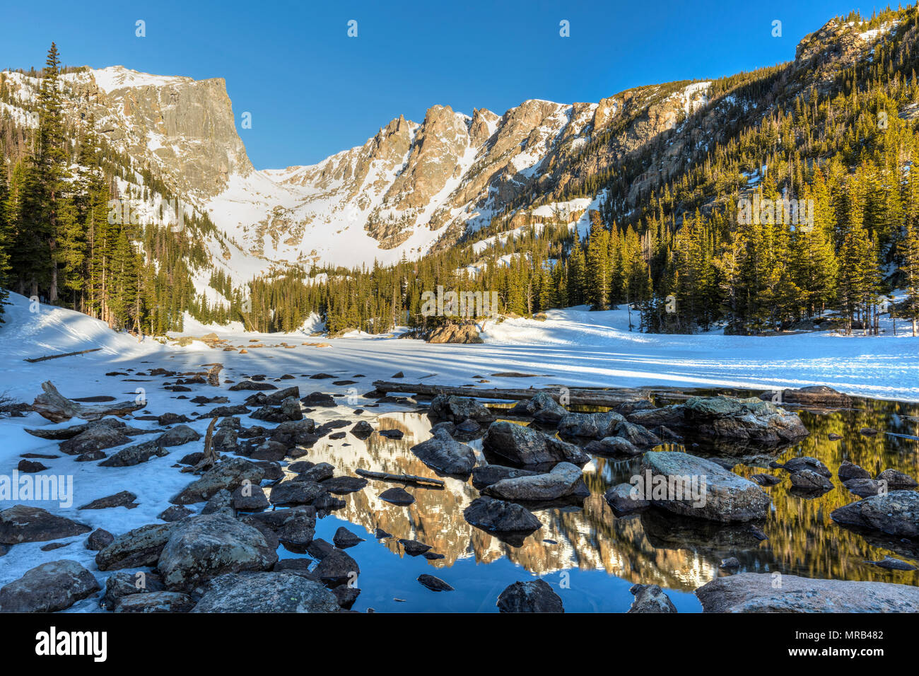 Soleil du matin sur pic Hallett est reflétée dans la moitié dans le lac gelé Dream Rocky Mountain National Park, Colorado Banque D'Images