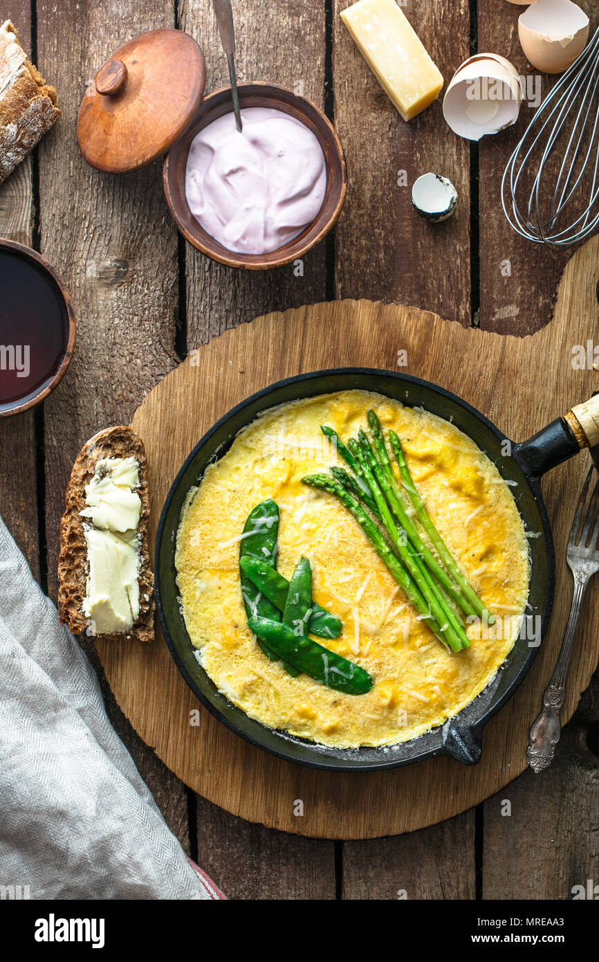 Frittata aux asperges vertes, pois sur poêle, vue de dessus, style rustique. Banque D'Images