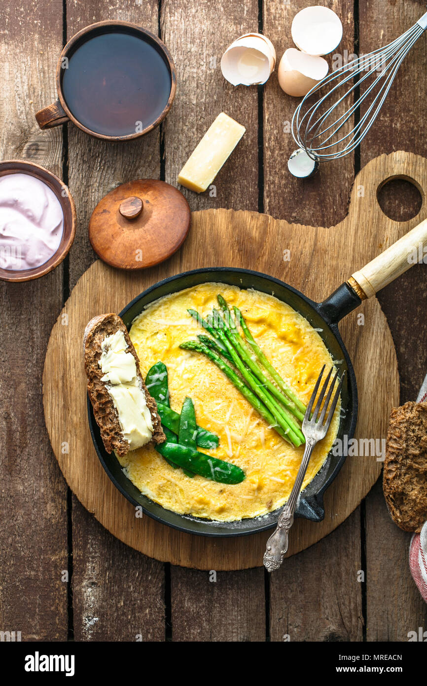 Omelette aux asperges vertes, pois sur poêle, vue de dessus, style rustique. Banque D'Images