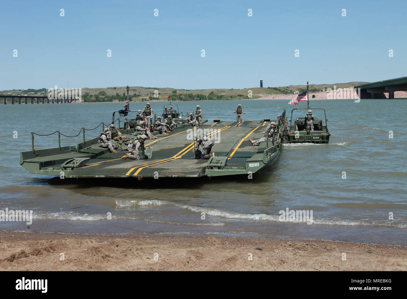 Les soldats de l'Armée américaine à la 200e compagnie du génie, la Garde nationale du Dakota du Sud, se préparer pour charger des véhicules militaires de la Garde nationale du Kansas sur ruban à l'amélioration de la passerelle pendant une opération de passage de la rivière à l'appui de Coyote d'or, Chambellan, S.D., 10 juin 2017. Le Coyote d'or l'exercice est un trois-phase, axée sur des mises en exercice mené dans les Black Hills du Dakota du Sud et le Wyoming, qui permet de se concentrer sur les commandants de mission besoins essentiels concernant la tâche, les tâches et les exercices de guerrier. Banque D'Images