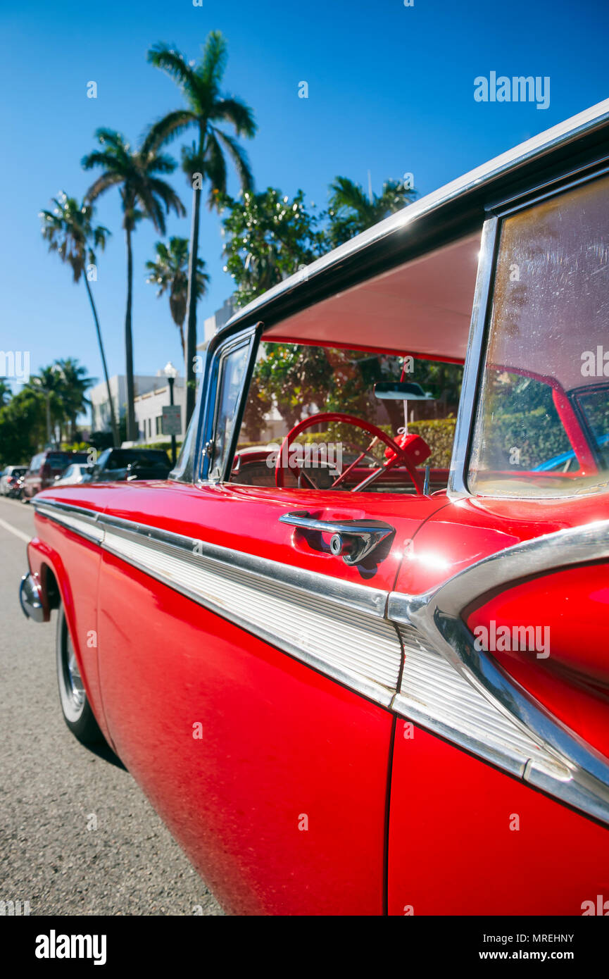 Abstract shot of red vintage détail voiture garée dans la rue à Miami Beach avec fond de bâtiments art-déco et de palmiers. Banque D'Images