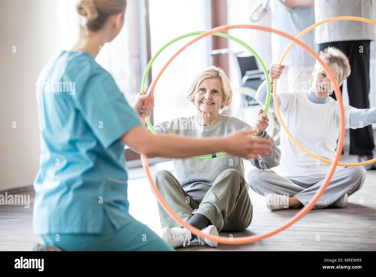 Physiothérapeute avec deux hauts femmes occupant des cerceaux en plastique. Banque D'Images