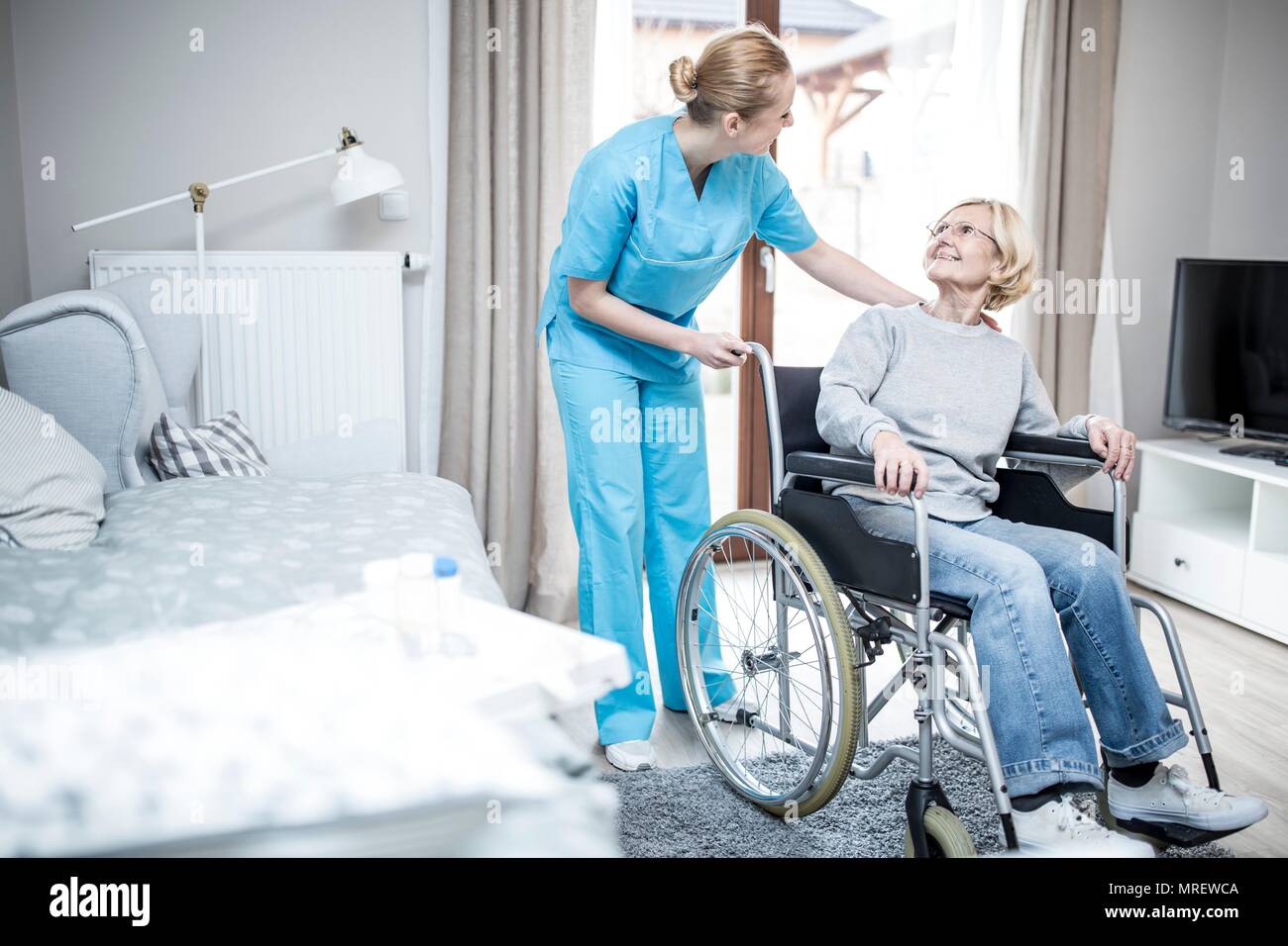 Senior woman in wheelchair with care worker en maison de soins. Banque D'Images