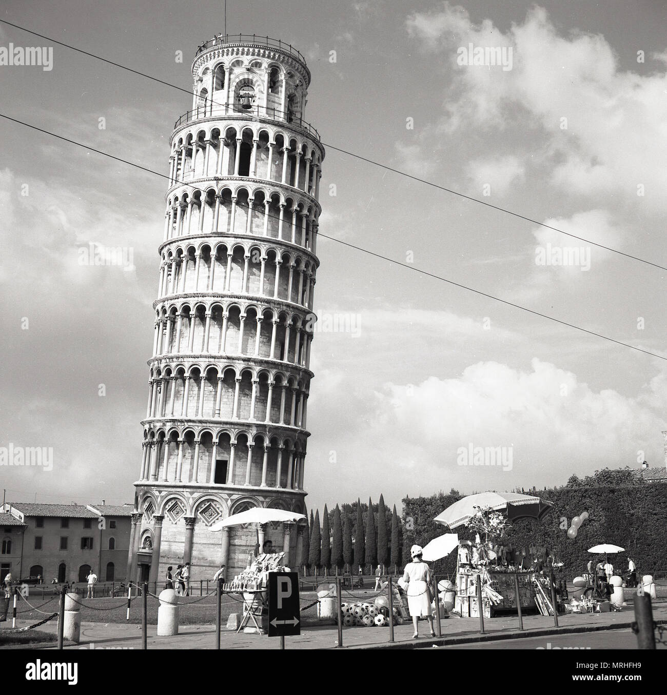 Années 1950, vue historique, les vendeurs de rue à l'extérieur de la Tour de Pise, Italie. Le campanile ou pose libre clocher est célèbre dans le monde entier pour son inclinaison imprévue, due à l'insuffisance de fondation sur sol mou lorsque sa a été construit. Sauvée d'un coup d'artillerie pendant la seconde guerre mondiale, de sorte que l'histoire continue, parce qu'il était considéré comme trop belle pour détruire, l'industrie touristique de Pise est à jamais reconnaissants. Banque D'Images