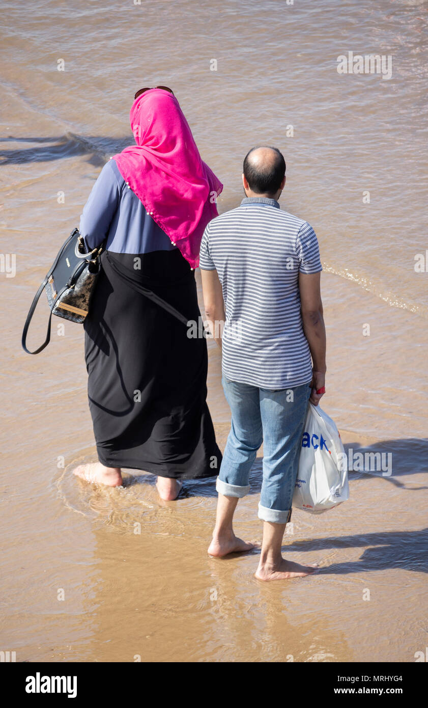 Femme portant un foulard hijab pagayant sur la plage. Angleterre, Royaume-Uni Banque D'Images