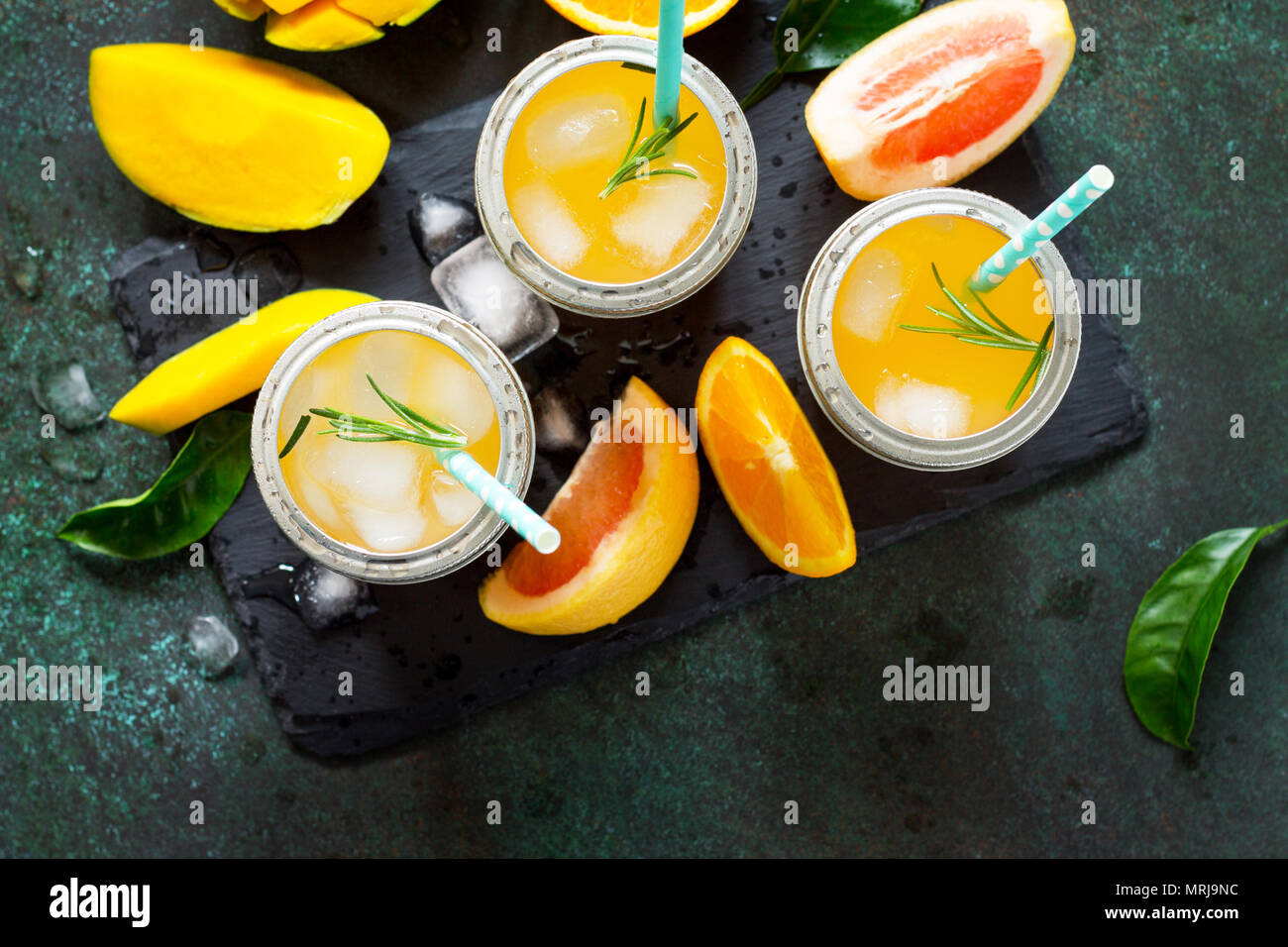 Des cocktails d'été d'agrumes et de mangue, boisson froide ou un verre avec de la glace sur une pierre sombre arrière-plan. Banque D'Images