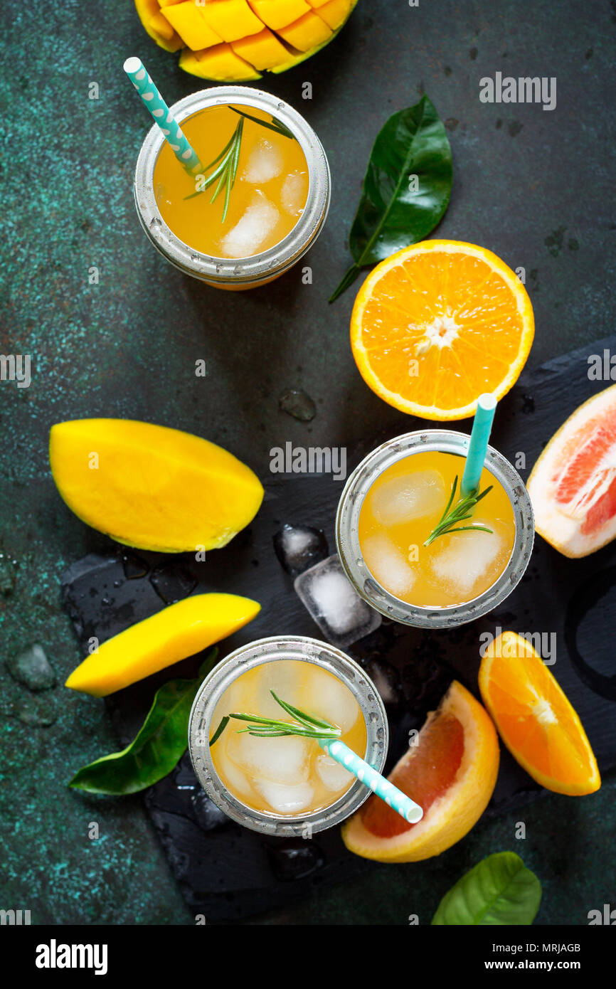 Des cocktails d'été d'agrumes et de mangue, boisson froide ou un verre avec de la glace sur une pierre sombre arrière-plan. Banque D'Images