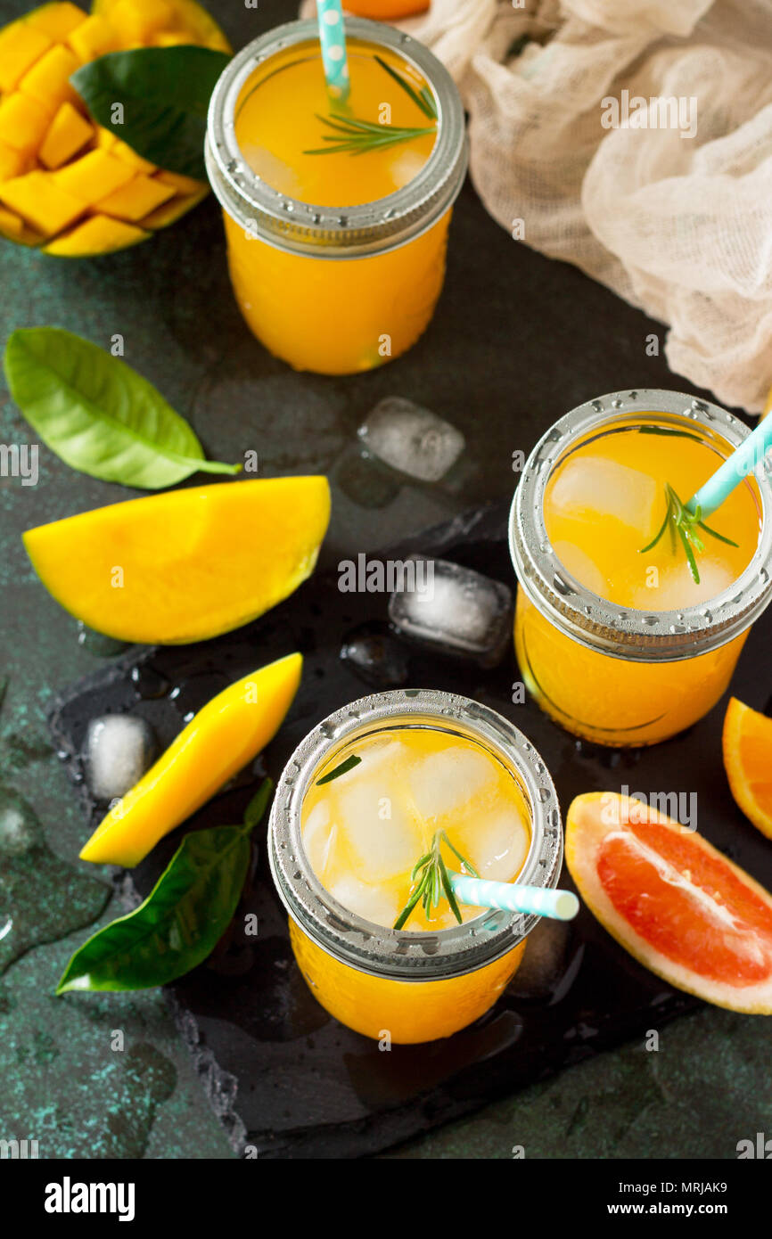 Des cocktails d'été d'agrumes et de mangue, boisson froide ou un verre avec de la glace sur une pierre sombre arrière-plan. Banque D'Images
