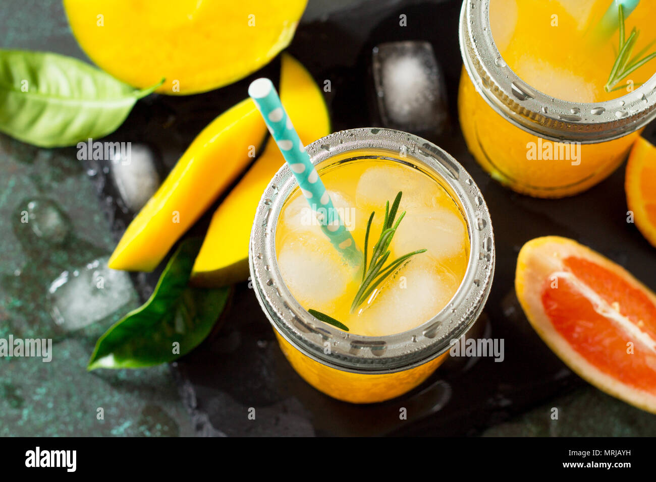 Des cocktails d'été d'agrumes et de mangue, boisson froide ou un verre avec de la glace sur une pierre sombre arrière-plan. Banque D'Images