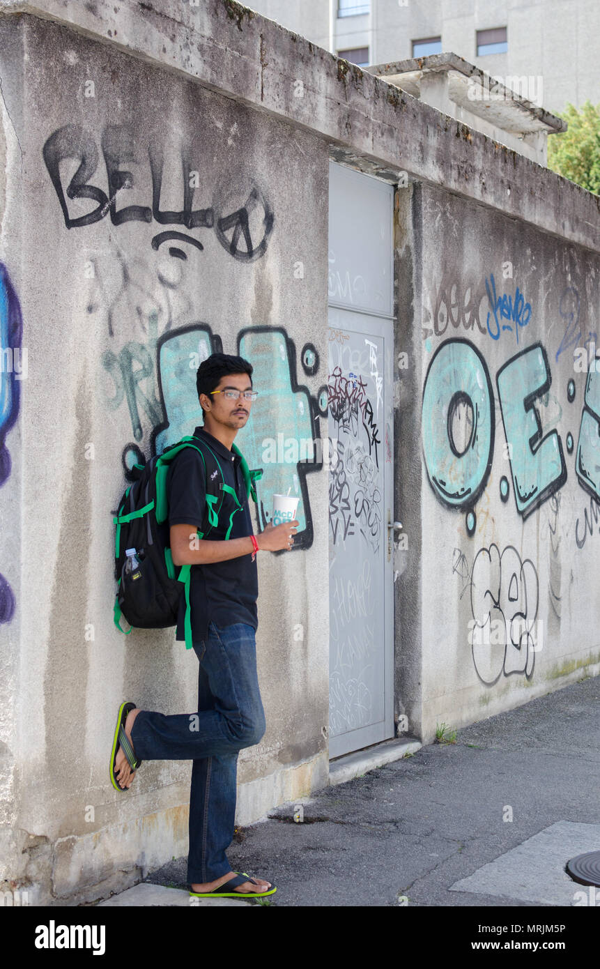 Portrait de jeune adulte jeune Indien posant contre un mur de graffiti avec sac à dos, à la recherche vers la caméra. Banque D'Images