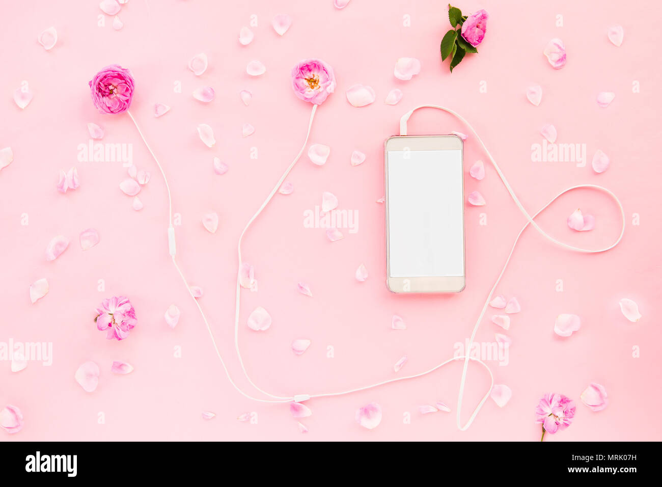 Présentation de la mode romantique - Vue de dessus avec casque blanc rose rose fleurs, smartphone et des pétales de rose sur le fond rose. Se détendre et délicate soun Banque D'Images