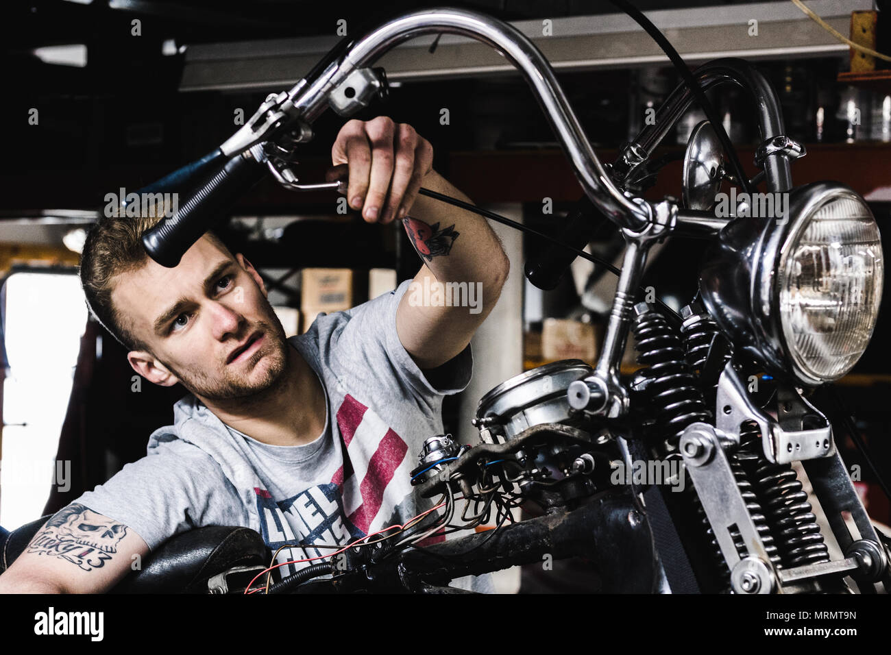 Un mécanicien travaillant sur sa moto Banque D'Images