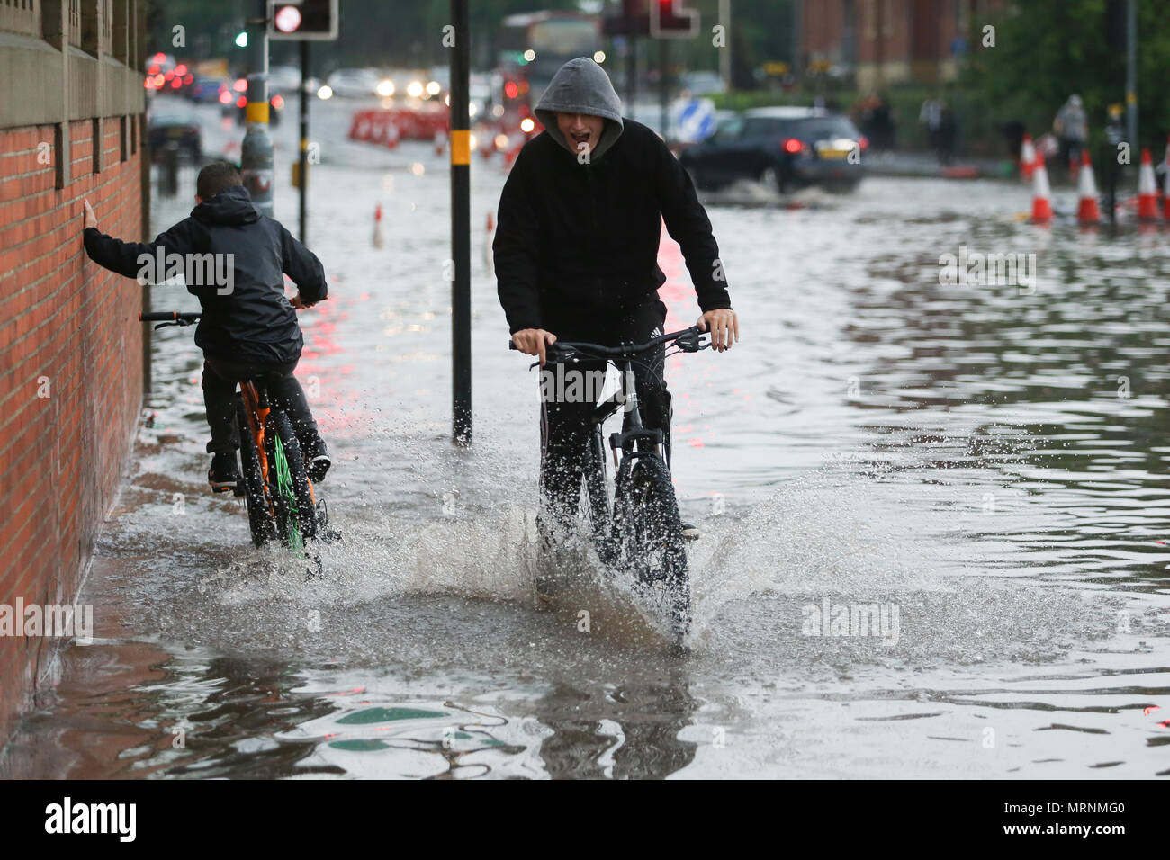 Deux garçons à vélo dans l'eau des crues, Birmingham UK Banque D'Images