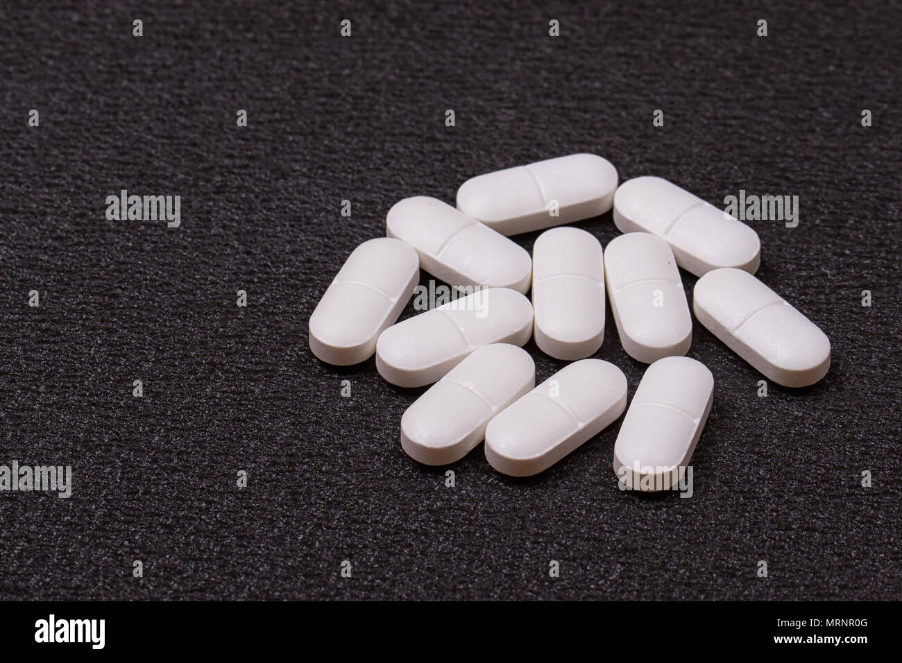 Close up pilules blanches sur fond noir. Banque D'Images