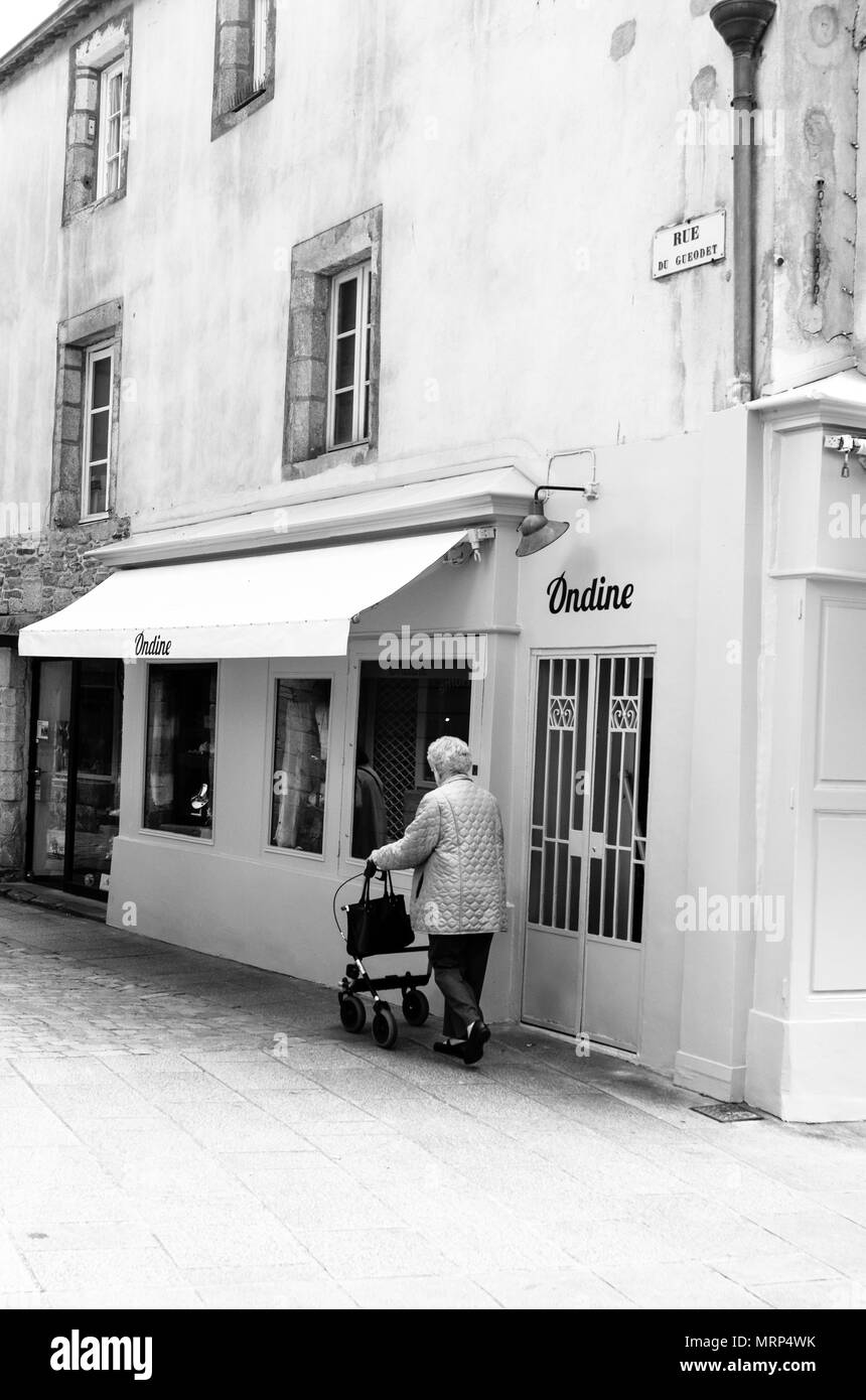 Une femme âgée avec une marchette à roulettes dans une rue calme à Quimper, Bretagne, France. B&W Banque D'Images