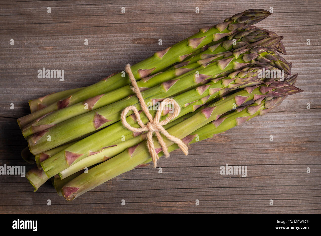D'en haut de l'asperge verte composée en heap et attaché avec une chaîne d'artisanat sur table en bois Banque D'Images