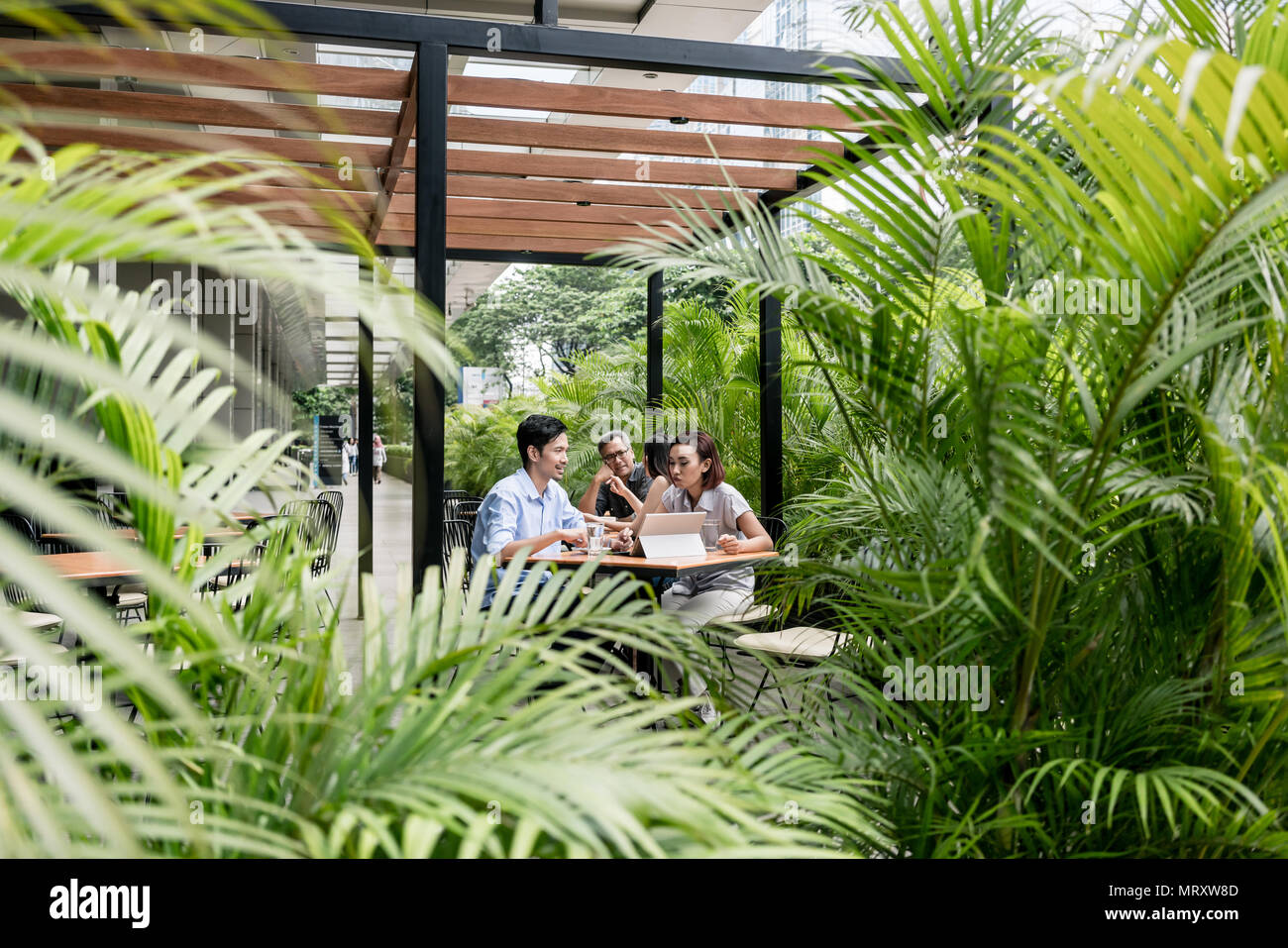 Les gens assis à l'extérieur à une cafétéria moderne Banque D'Images