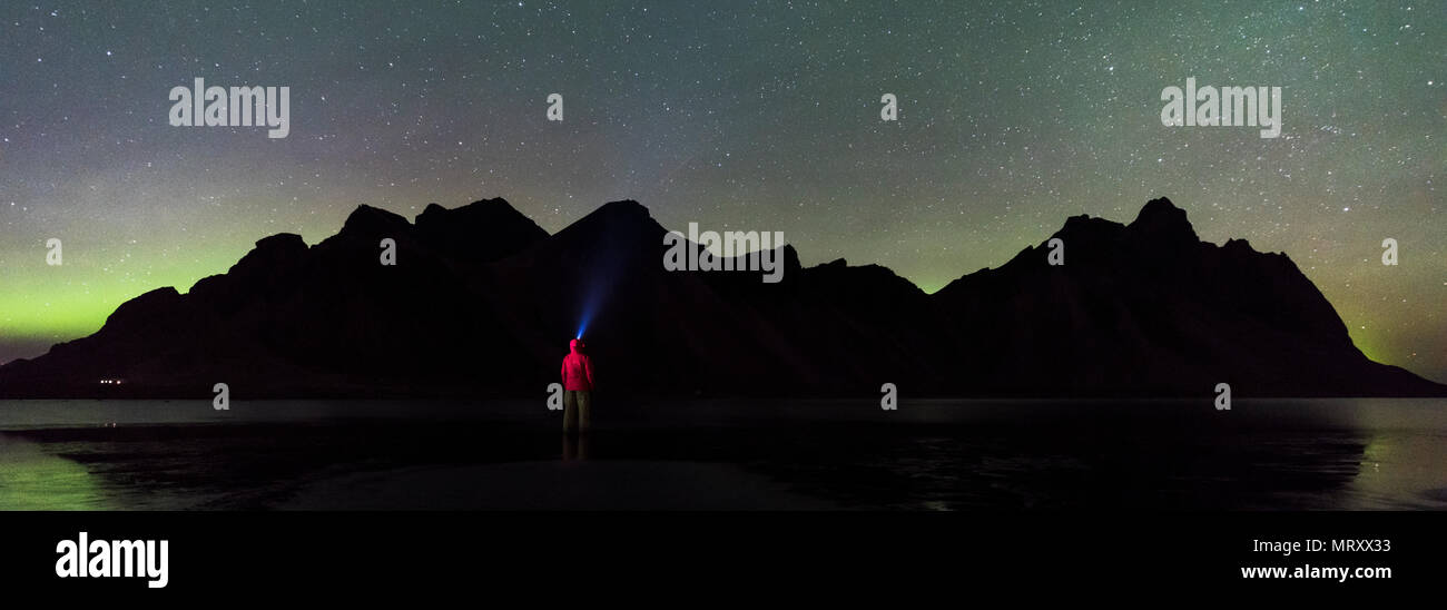 Stokksnes, Hofn, Islande, Islande de l'Est. Un homme debout sur la plage le soir en regardant le northern lights et Vestrahorn mountain Banque D'Images