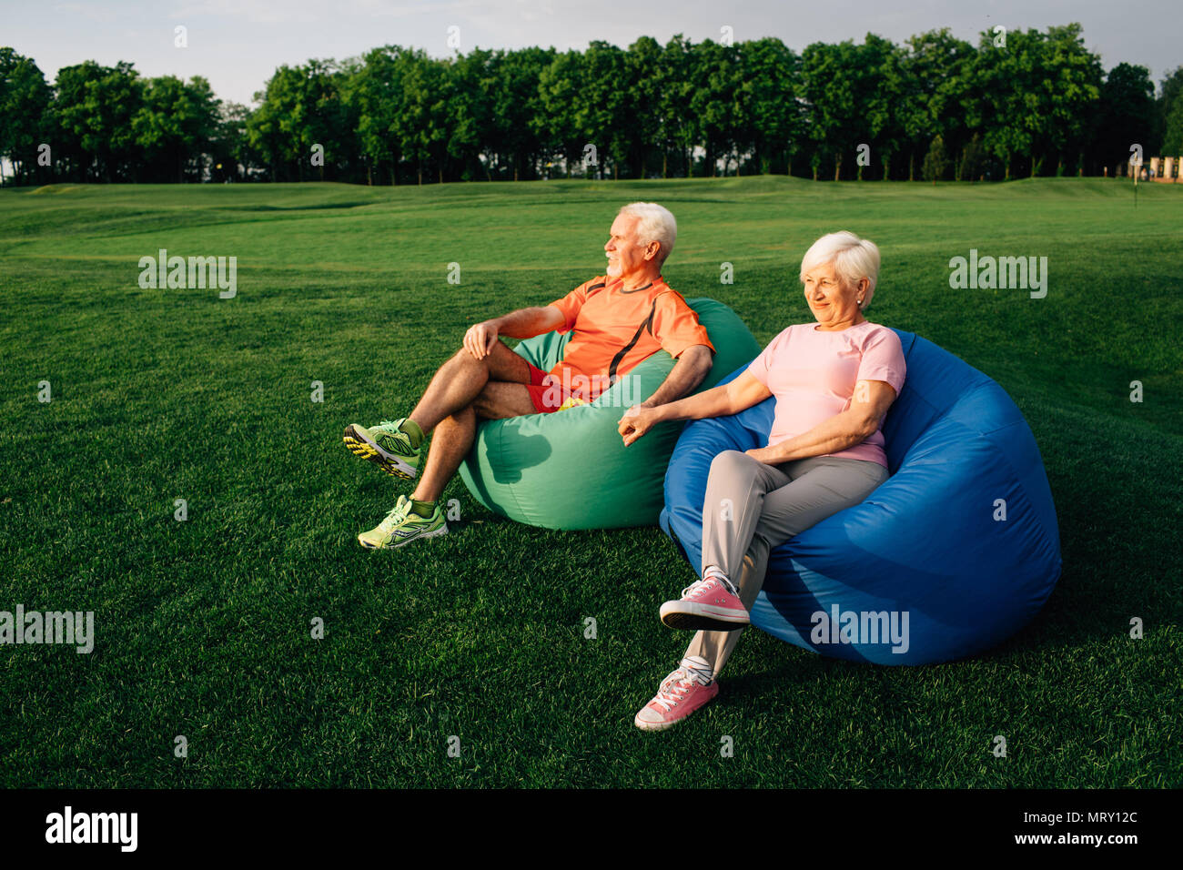 Couple assis sur des poufs sur l'herbe Banque D'Images