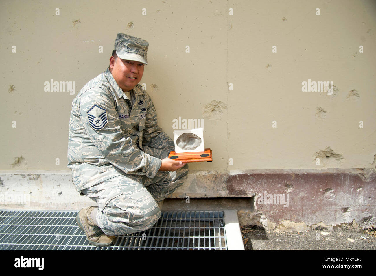 Le sergent-chef de l'US Air Force. Ronald Wabinga, de Kapa'a, Kauai, membre de l'escadron de Génie Civil 624th, affiche une reproduction d'une marque du trou de balle, ou, de dépressions coniques causées par des éclats d'une bombe de l'Imperial attaque japonaise sur Oahu 7 décembre 1941 au Quartier général des forces de l'air du Pacifique, d'une base commune Pearl Harbor-Hickam, New York, 13 avril 2017. Wabinga passe ses temps libres à faire ces cadeaux d'adieu pour aider les gens à se souvenir de Hawaii et les hommes et femmes qui ont donné leur vie pour leur pays. Banque D'Images