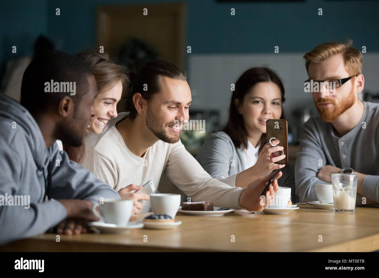 Multi-ethnic group of friends talking and using smartphones en m Banque D'Images