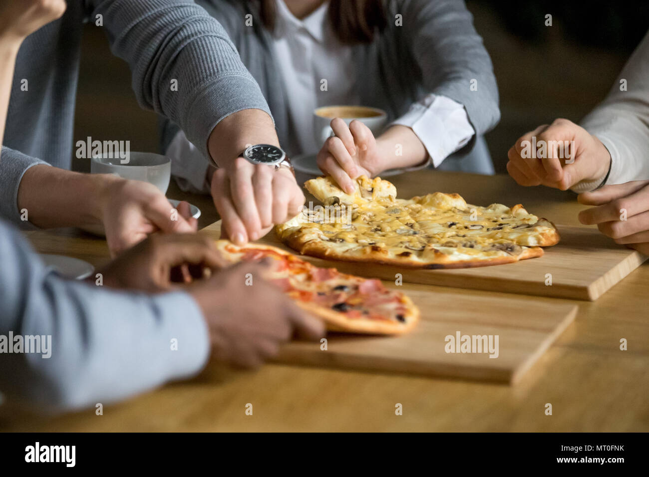 Les mains de diverses personnes prenant des tranches de pizza pizzeria à manger Banque D'Images