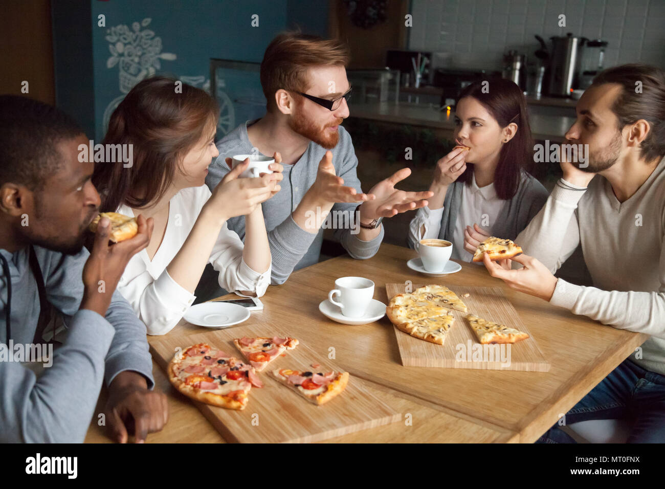 Guy roux parler à divers friends eating pizza dans une pizzeria Banque D'Images