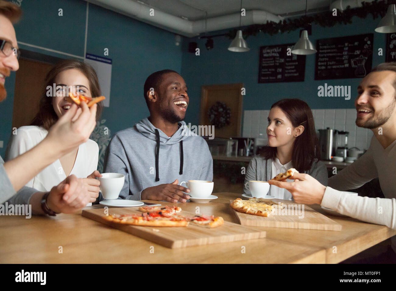 Heureux multiraciale friends laughing millénaire toget eating pizza Banque D'Images