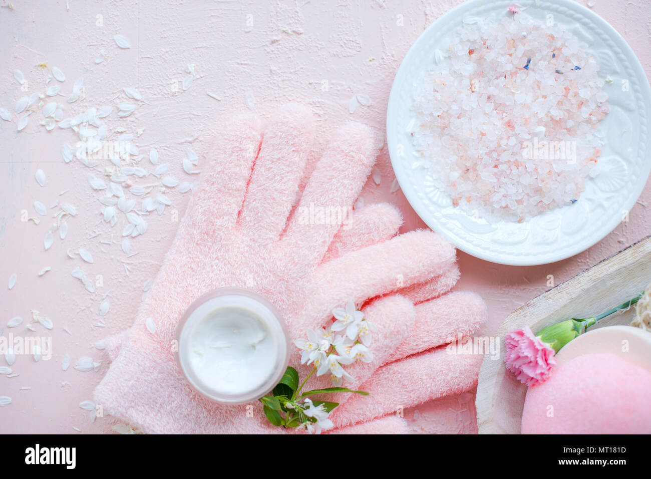 Soins des mains spa, sel de mer et des gants. Les fleurs sont blanches.  Fond rose Photo Stock - Alamy