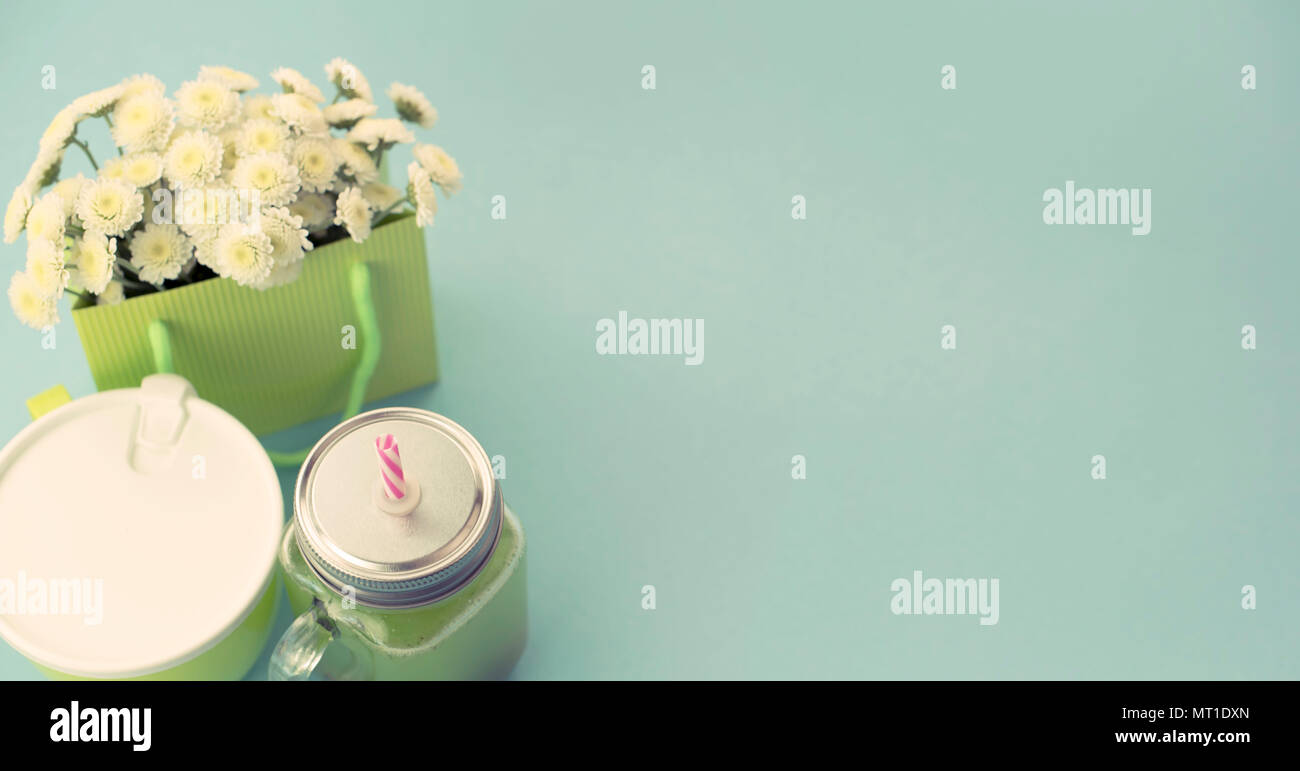 Tasse en verre de bannière avec un tube de smoothies frais.Le récipient avec du porridge pour le petit-déjeuner ou le déjeuner. Soupe repas chrysanthèmes naturelles sur bleu ba Banque D'Images