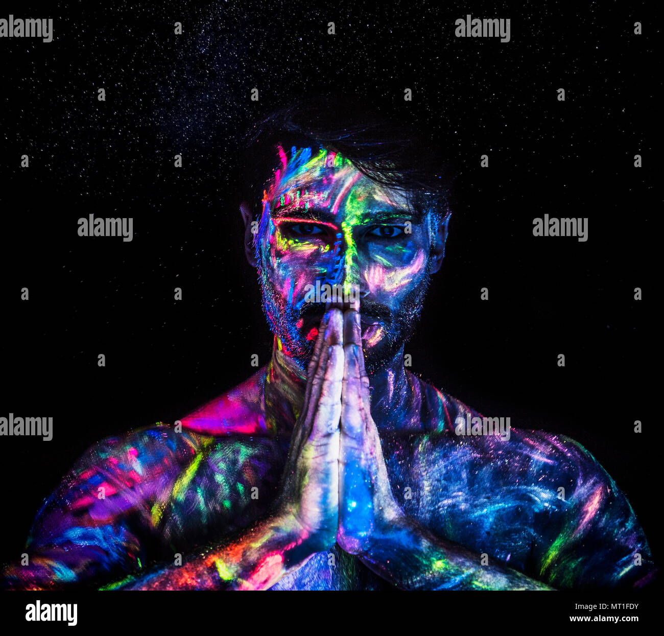 Jeune homme peint à la peinture fluorescente sur le visage et le torse  musclé, dans le studio photo grâce à la lumière UV Photo Stock - Alamy