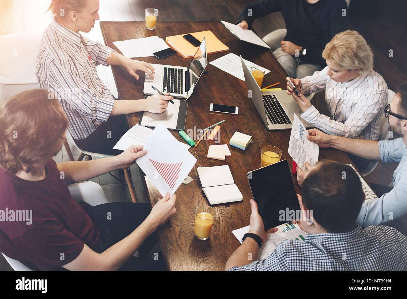 Le travail conjoint de jeunes collègues sur une grande table avec différents gadgets électroniques et ordinateurs portables. Discussion d'une nouvelle équipe de démarrage d'entreprise Banque D'Images