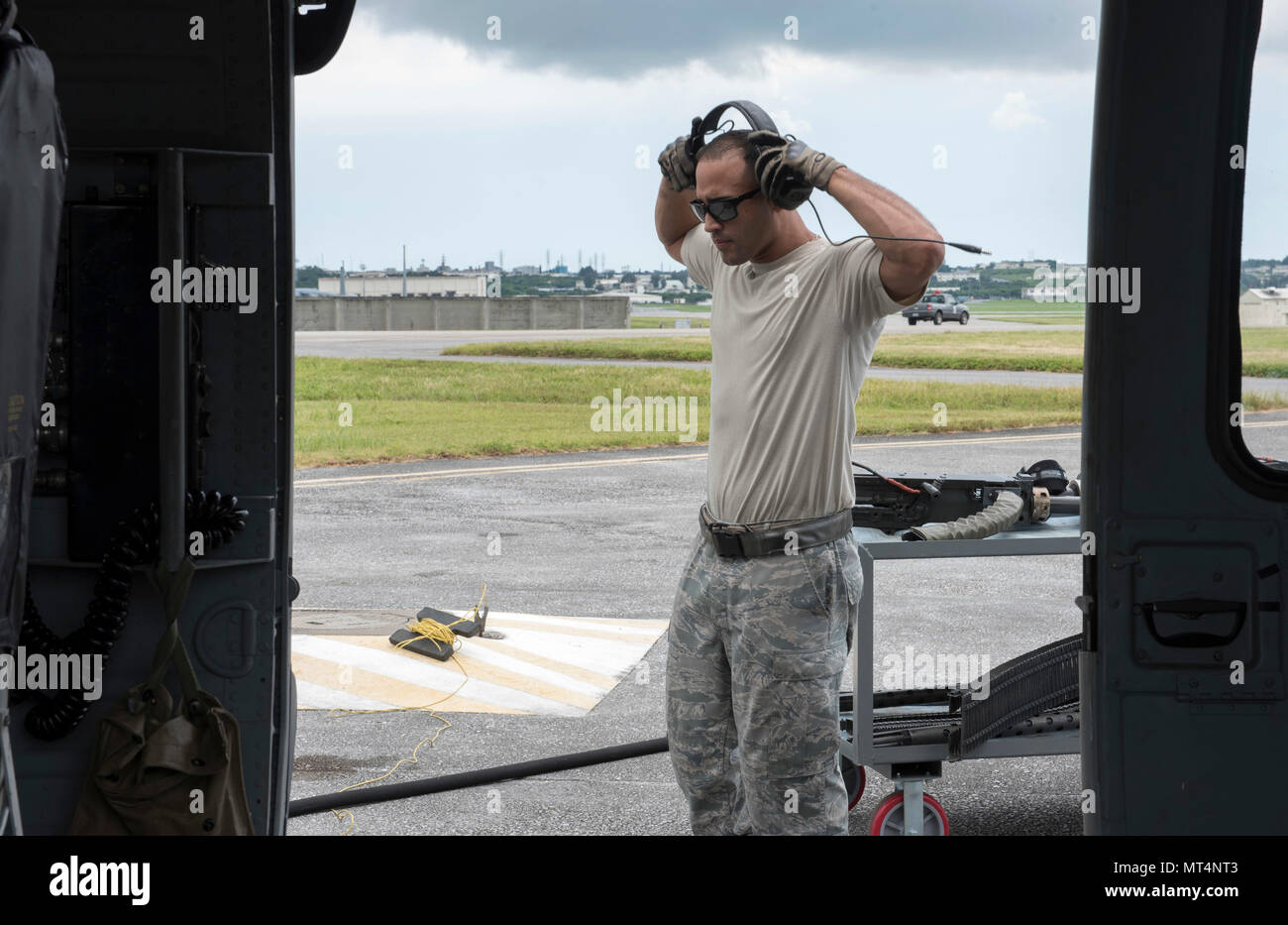 U.S. Air Force Tech. Le Sgt. Josean Arce, 33e Unité de maintenance d'hélicoptères section armes expediter armes aube, la protection des oreilles comme un bras de son équipe HH-60 Pave Hawk de la 33e Escadron de sauvetage Le 26 juillet 2017, à Kadena Air Base, au Japon. La 33e rouge joue un rôle vital dans le maintien de la paix et de la stabilité dans la région du Pacifique en fournissant de l'avant la projection de puissance et de rechercher, de sauvetage et de récupération les capacités de mission. (U.S. Photo de l'Armée de l'air par les cadres supérieurs d'un membre de la John Linzmeier) Banque D'Images