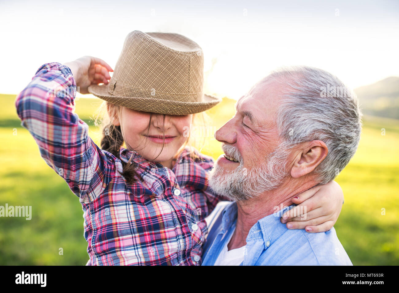 Une petite fille avec son grand-père à l'extérieur au printemps, la nature s'amusant. Banque D'Images
