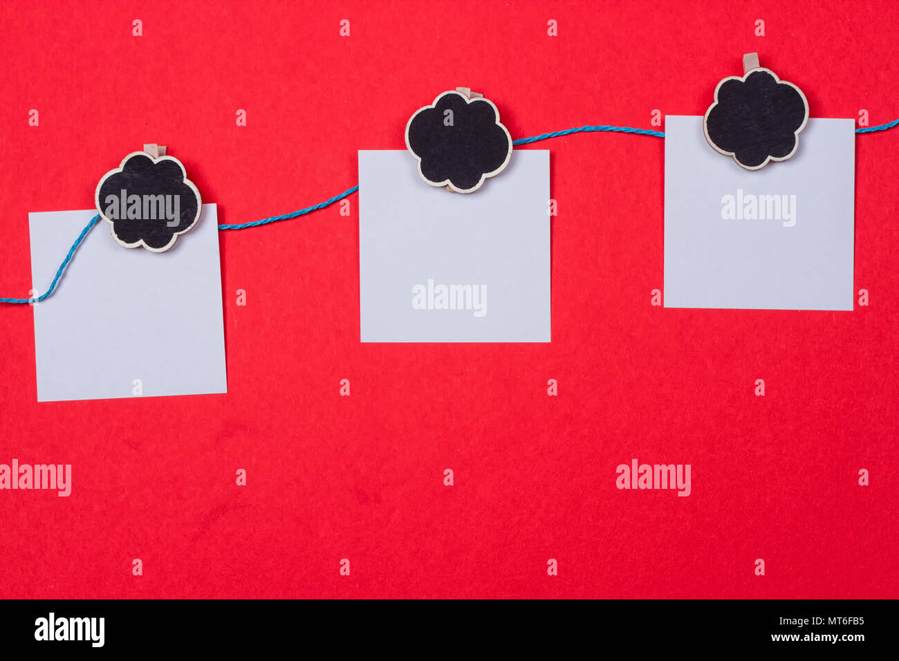 Clothespins, papiers avec une place pour l'écriture sur un fond rouge Banque D'Images