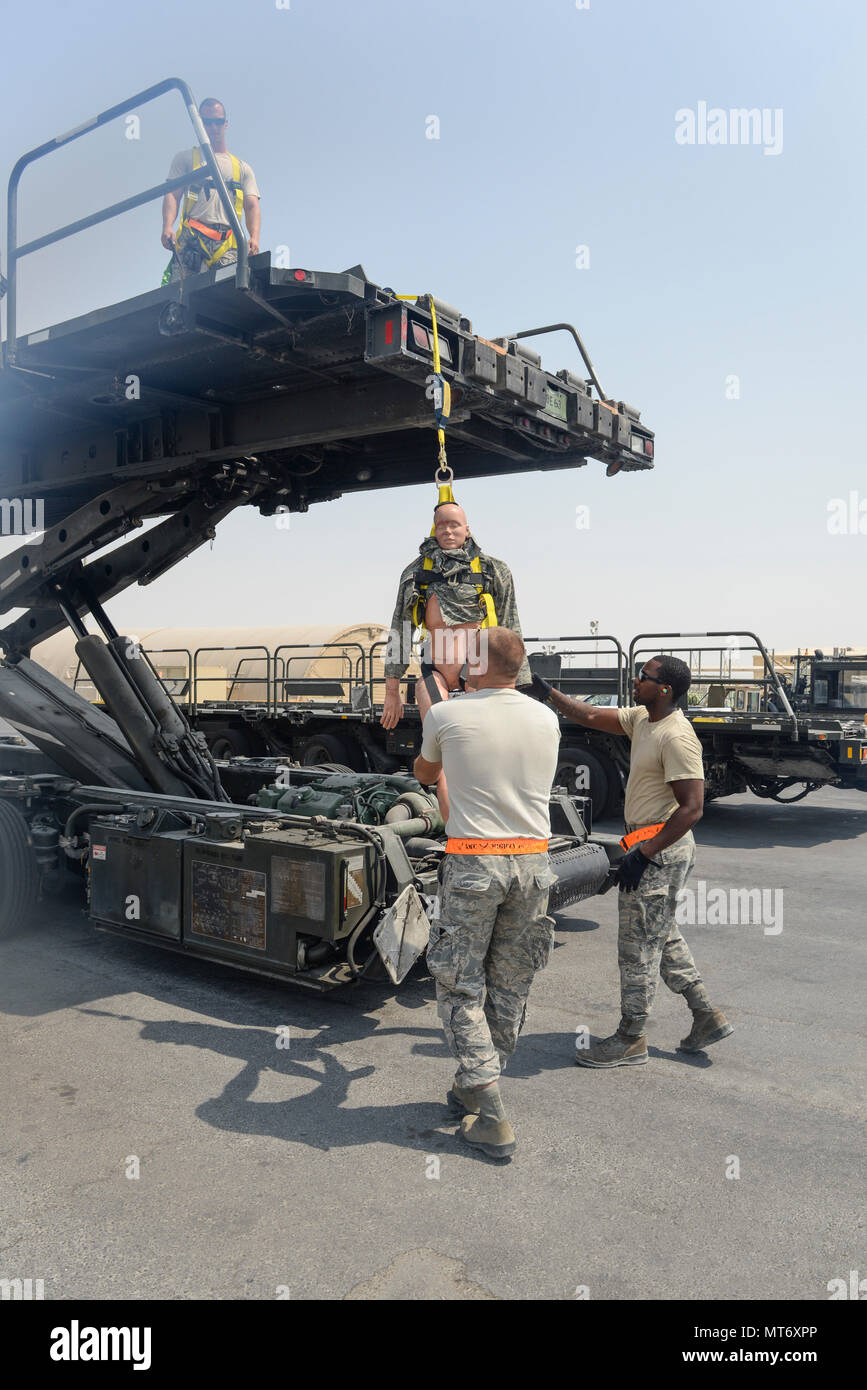 Les cadres supérieurs de l'US Air Force Airmen Russell Robinson, center, Columbus et Johnson, droite, tenter de stabiliser un mannequin de formation Tech quelques instants après. Le Sgt. Cuisine David poussa le mannequin de formation à partir d'un 60K Tunner chargeur de fret au cours d'un exercice de protection de l'automne à Al Udeid Air Base, Qatar, le 8 septembre 2017. Robinson, Johnson et de la cuisine, du transport aérien de la marine affecté à la 8e Escadron expéditionnaire de la mobilité de l'air, ont participé à l'exercice qui a eu lieu dans le cadre de la 8e SEGO fall protection de la formation et de plan de sauvetage. (U.S. Air National Guard photo de Tech. Le Sgt. Bradly A. Schneider/libérés) Banque D'Images