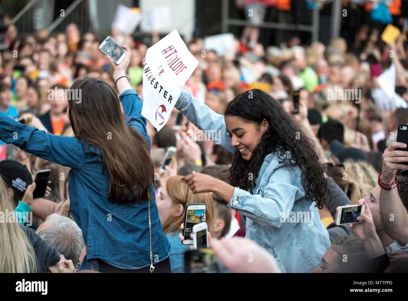 Deux jeunes filles s'asseoir sur les épaules pendant le concert chorale Concert de Manchester se souvenir des victimes de l'arène à la bombe à Manchester, Angleterre, le 22 mai 2018. Le prince William et le Premier ministre britannique Theresa peuvent se joindre à d'autres politiciens, ainsi que les membres de la famille de ceux qui ont été tués, et les premiers intervenants sur les lieux de l'attaque terroriste, alors que des milliers de personnes se sont réunies à Manchester mardi sur le premier anniversaire d'une attaque terroriste dans la ville qui a laissé 22 morts. Banque D'Images