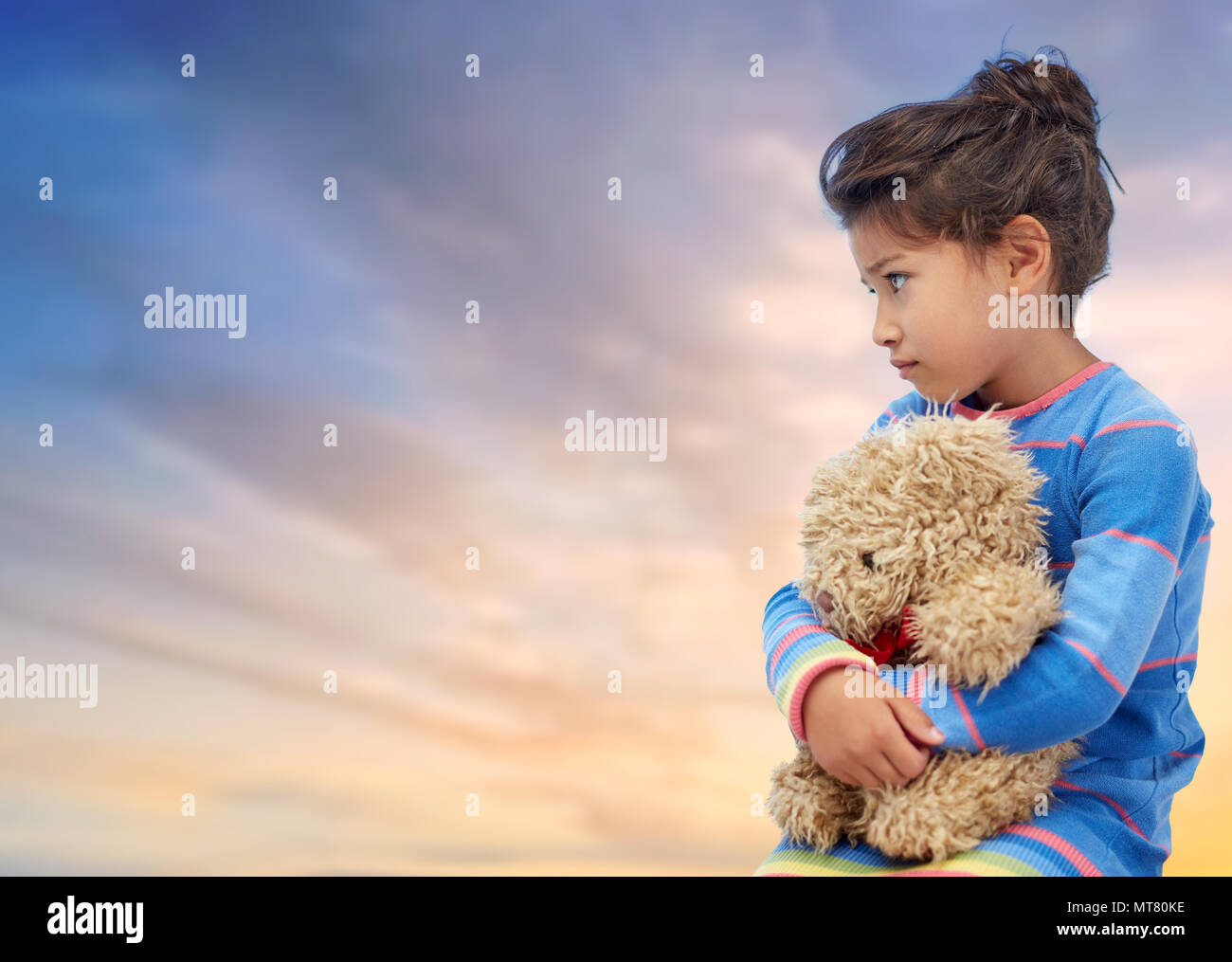 Triste petite fille avec nounours plus de ciel du soir Banque D'Images